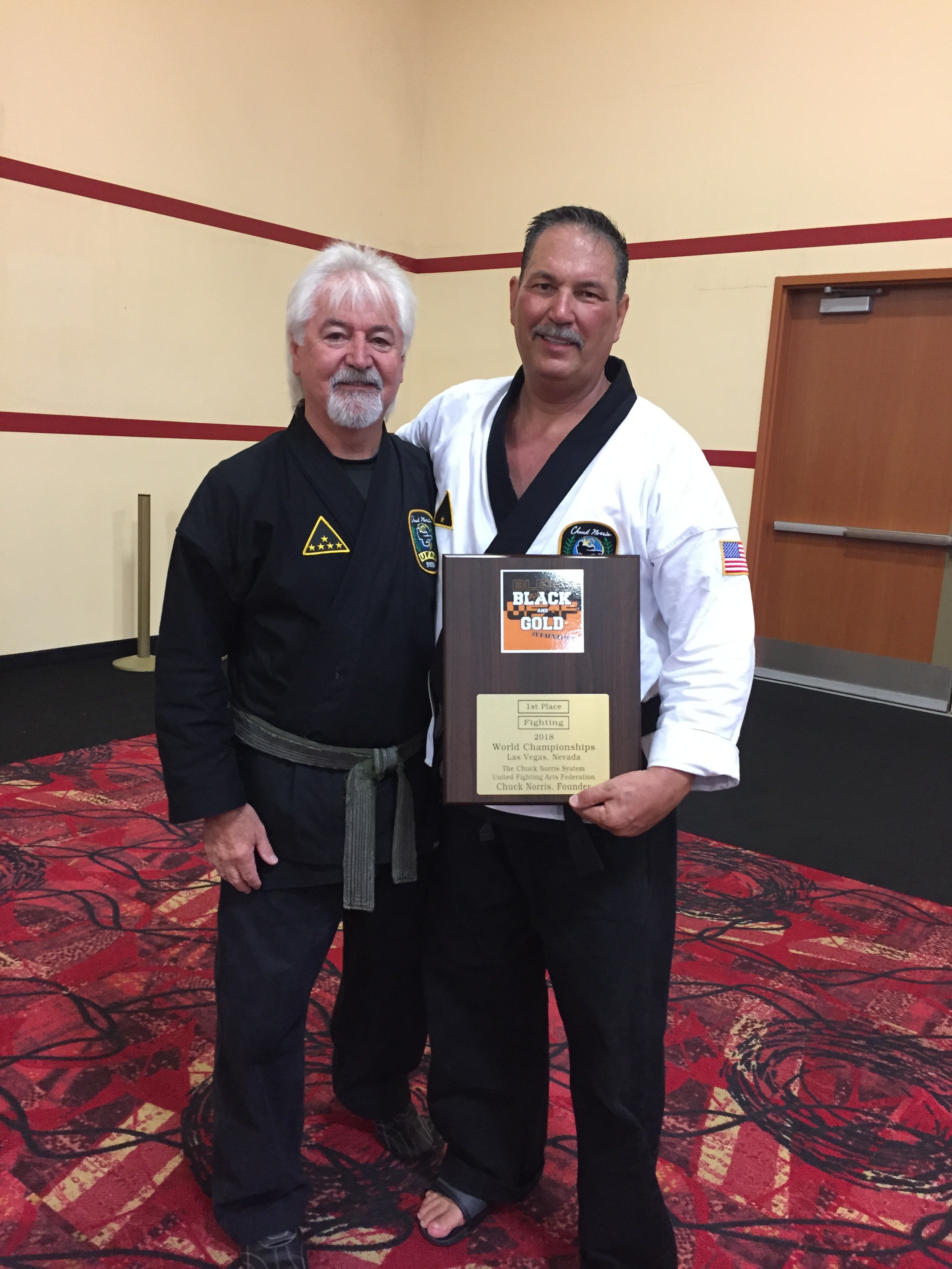 Two martial arts instructors holding Black Gold World Championships plaque