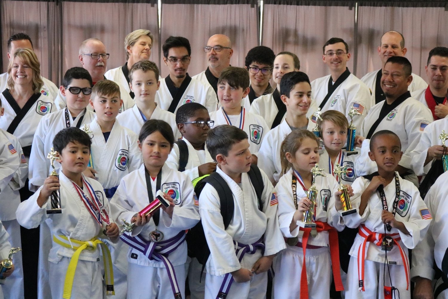 Large group of karate students with trophies and medals at tournament